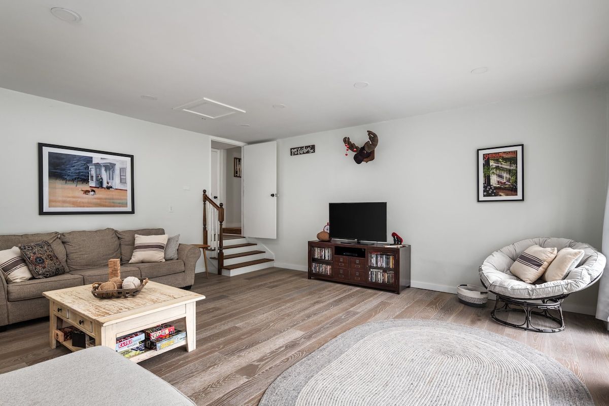 Una sala de estar con sofá, mesa de centro, mueble para televisión y una silla.