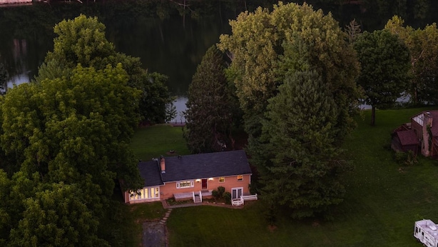 Una casa amb un moll a la vora d'un llac, envoltada d'arbres.