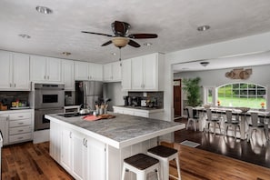 A modern kitchen with white cabinets, a central island, and a dining area with bar stools.