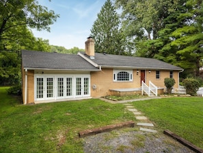 Een gelijkvloers huis met een veranda, schoorsteen en een verzorgd gazon.