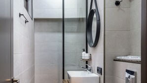 Een moderne badkamer met een houten wastafelmeubel, toilet en douche.