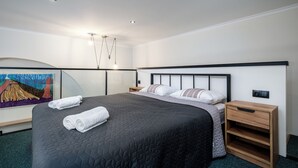 Een moderne hotelkamer met een groot bed, een nachtkastje en een schilderij aan de muur.