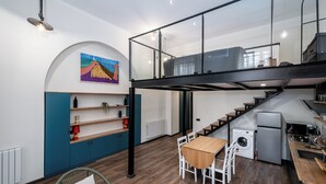 Een moderne keuken met een eethoek, een wasmachine en een trap naar een verdieping erboven.