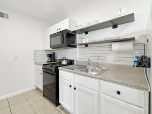 A modern kitchen with white cabinets, a stainless steel sink, and a microwave.