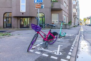 Ein Fahrrad steht auf einem markierten Radweg vor einem Gebäude mit der Aufschrift 'Raua'.