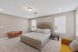 A bedroom with a bed, a nightstand, a chair, and a window.