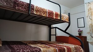 A bunk bed with a patterned bedspread, a small bedside table with a plant, and a wall-mounted picture frame. - Cozy Ground-Floor Apartment Near U Mondragón, Industrial Area (Real Solare)