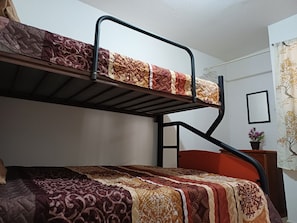 A bunk bed with a patterned bedspread, a small bedside table with a plant, and a wall-mounted picture frame. - Cozy Ground-Floor Apartment Near U Mondragón, Industrial Area (Real Solare)