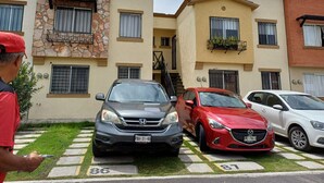 A multi-story residential building with a stone facade, multiple balconies, and a parking area with cars. - Cozy Ground-Floor Apartment Near U Mondragón, Industrial Area (Real Solare)