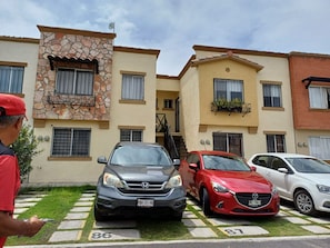 A multi-story residential building with a stone facade, multiple balconies, and a parking area with cars. - Cozy Ground-Floor Apartment Near U Mondragón, Industrial Area (Real Solare)