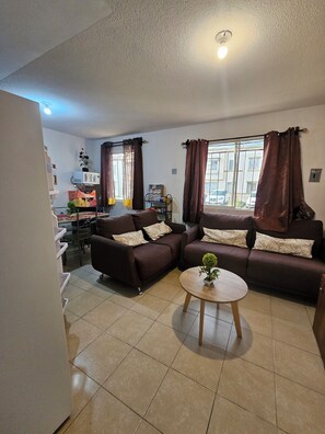 A living room with two sofas, a coffee table, and a window with curtains. - Cozy Ground-Floor Apartment Near U Mondragón, Industrial Area (Real Solare)