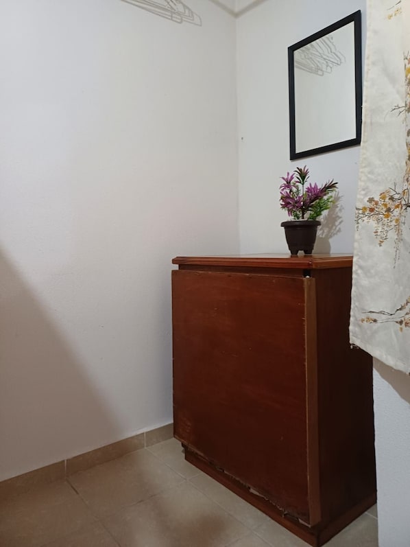 A corner room with a wooden cabinet, a potted plant, and a framed picture on the wall. - Cozy Ground-Floor Apartment Near U Mondragón, Industrial Area (Real Solare)