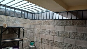 A room with a skylight, stone walls, a metal shelf with buckets, and a gas cylinder. - Cozy Ground-Floor Apartment Near U Mondragón, Industrial Area (Real Solare)