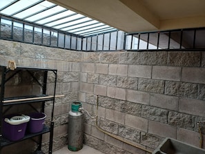 A room with a skylight, stone walls, a metal shelf with buckets, and a gas cylinder. - Cozy Ground-Floor Apartment Near U Mondragón, Industrial Area (Real Solare)