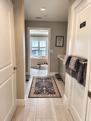 A hallway leading to a bedroom with a large window, a rug, and a towel rack. - The Grand Mariner: Waterfront + Boat Slip + Elevator Luxury Estate (St. Augustine)