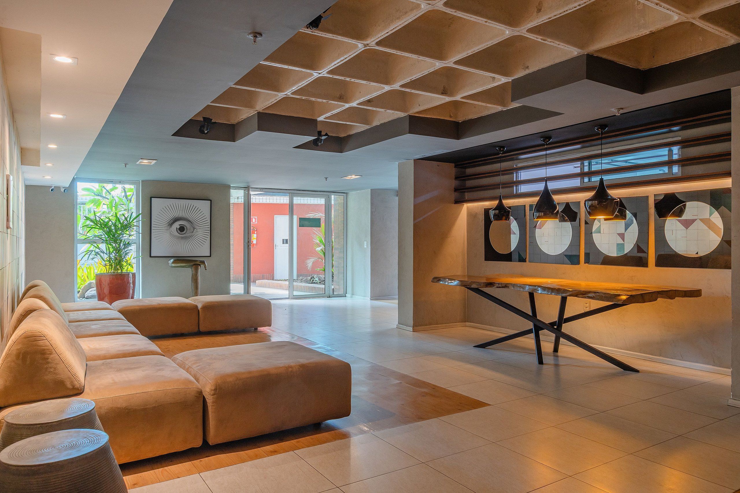 Un interior moderno con un sofá modular, una mesa de comedor y lámparas colgantes.
