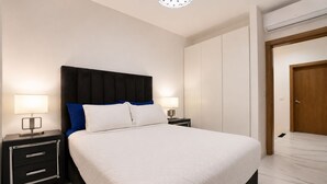Ein Hotelzimmer mit einem Bett, zwei Nachttischen mit Lampen, einem Kleiderschrank und einer Tür.