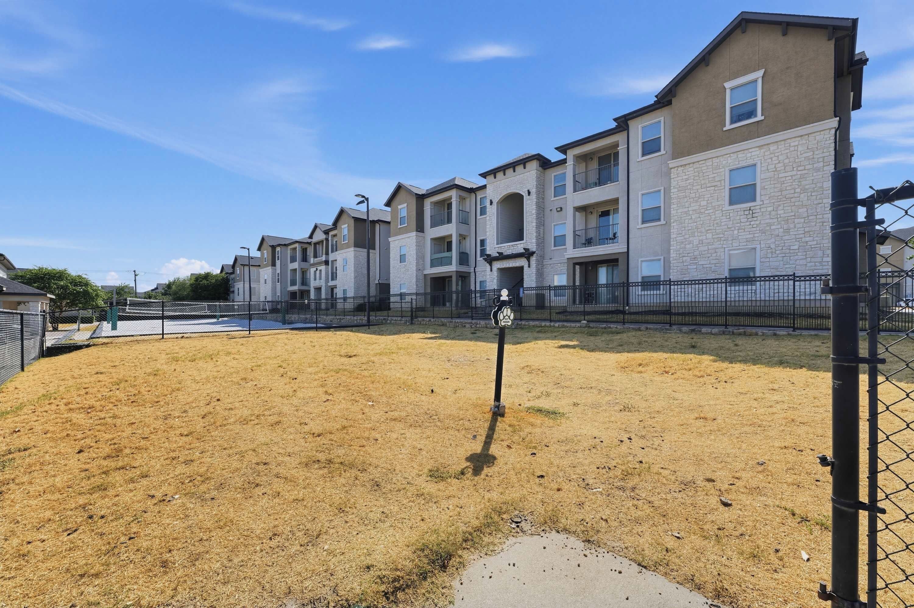 A residential building with multiple floors, balconies, and a fenced yard.