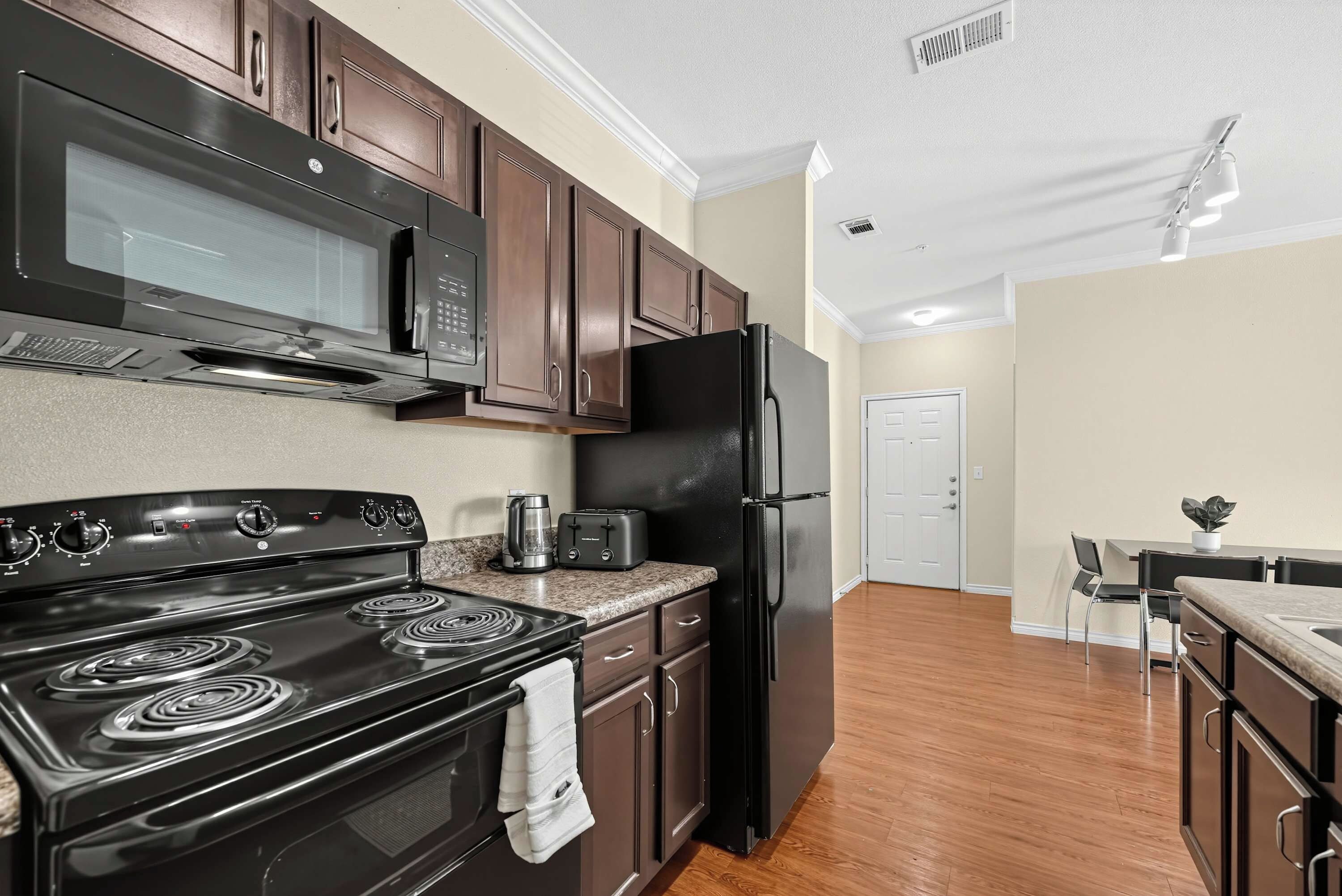 A modern kitchen with a stove, microwave, toaster, and refrigerator.