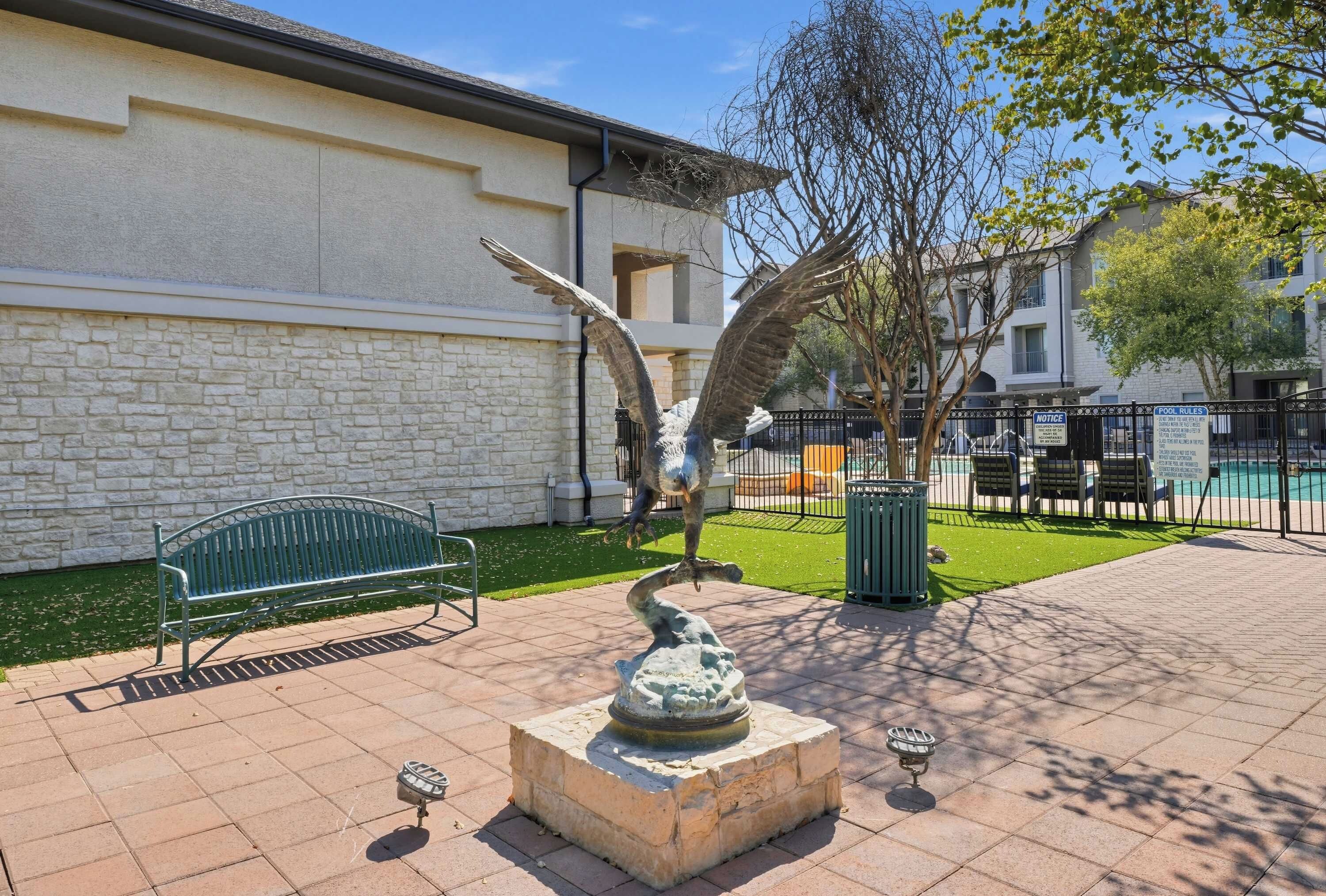 Ein Innenhof mit einer Steinsitzbank, einem Brunnen und einem Poolbereich mit einer Umzäunung.
