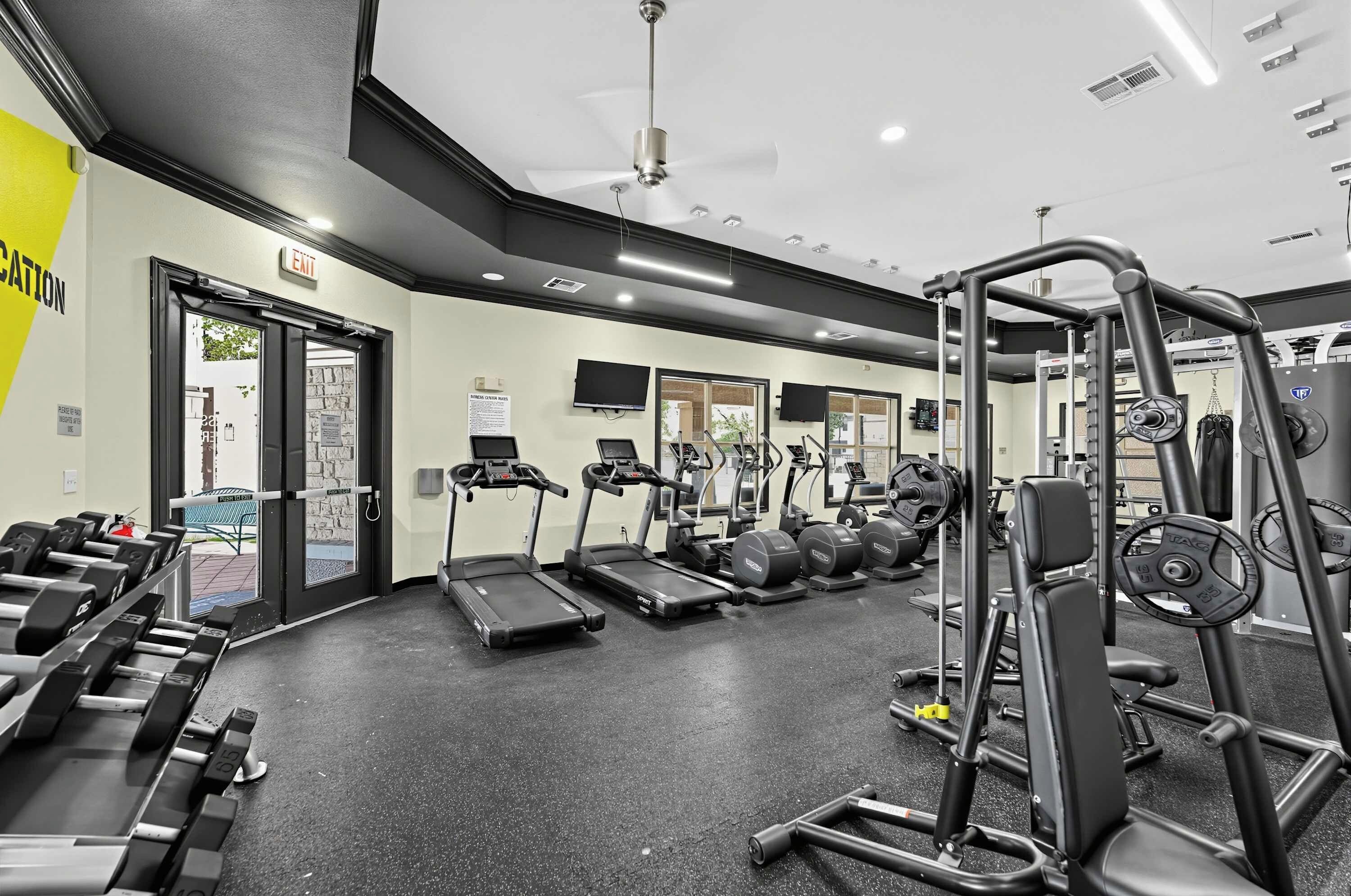 A gym with treadmills, weight machines, and dumbbells.
