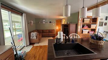 A kitchen with a wooden countertop, a sink, and a dining area with a table and chairs.