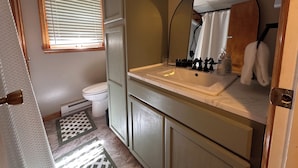 Et badeværelse med toilet, vask, spejl og håndklædestang.