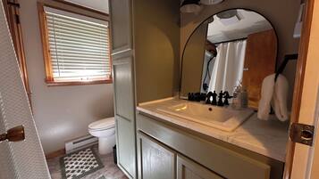 A bathroom with a toilet, sink, mirror, and towel rack.