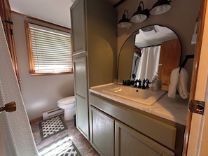 Bagno con servizi igienici, lavandino, specchio e portasciugamani.