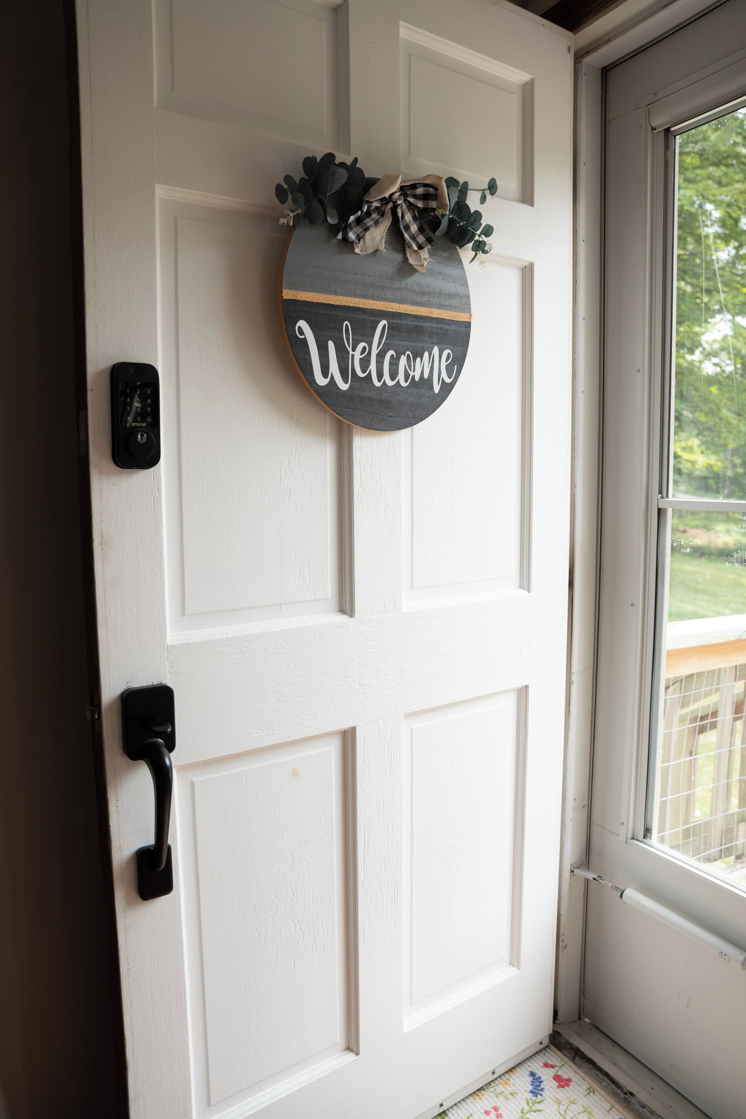 A white door with a 'Welcome' sign and a doorbell.