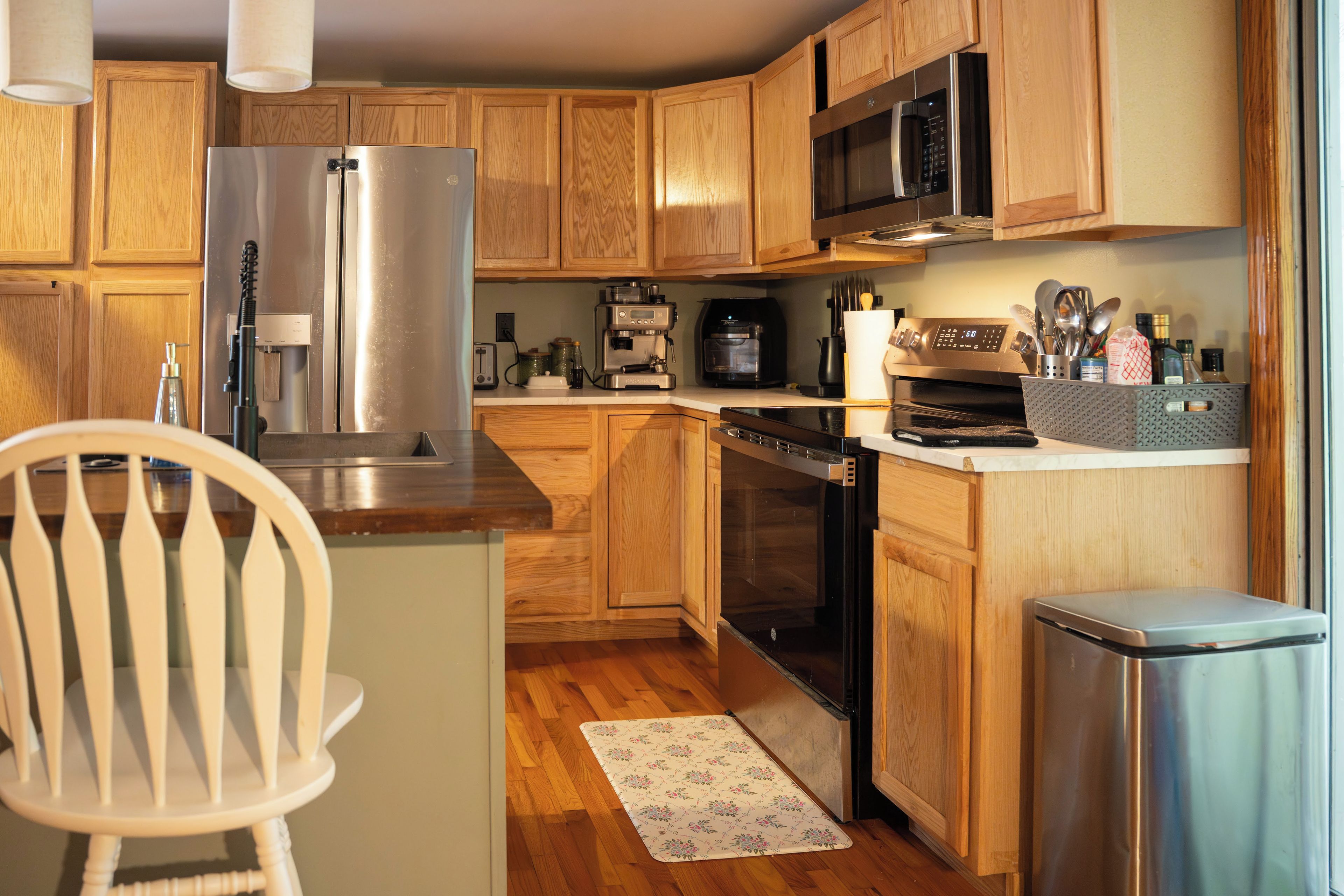Una cocina compacta con muebles de madera, un refrigerador de acero inoxidable, una cafetera y un lavavajillas.