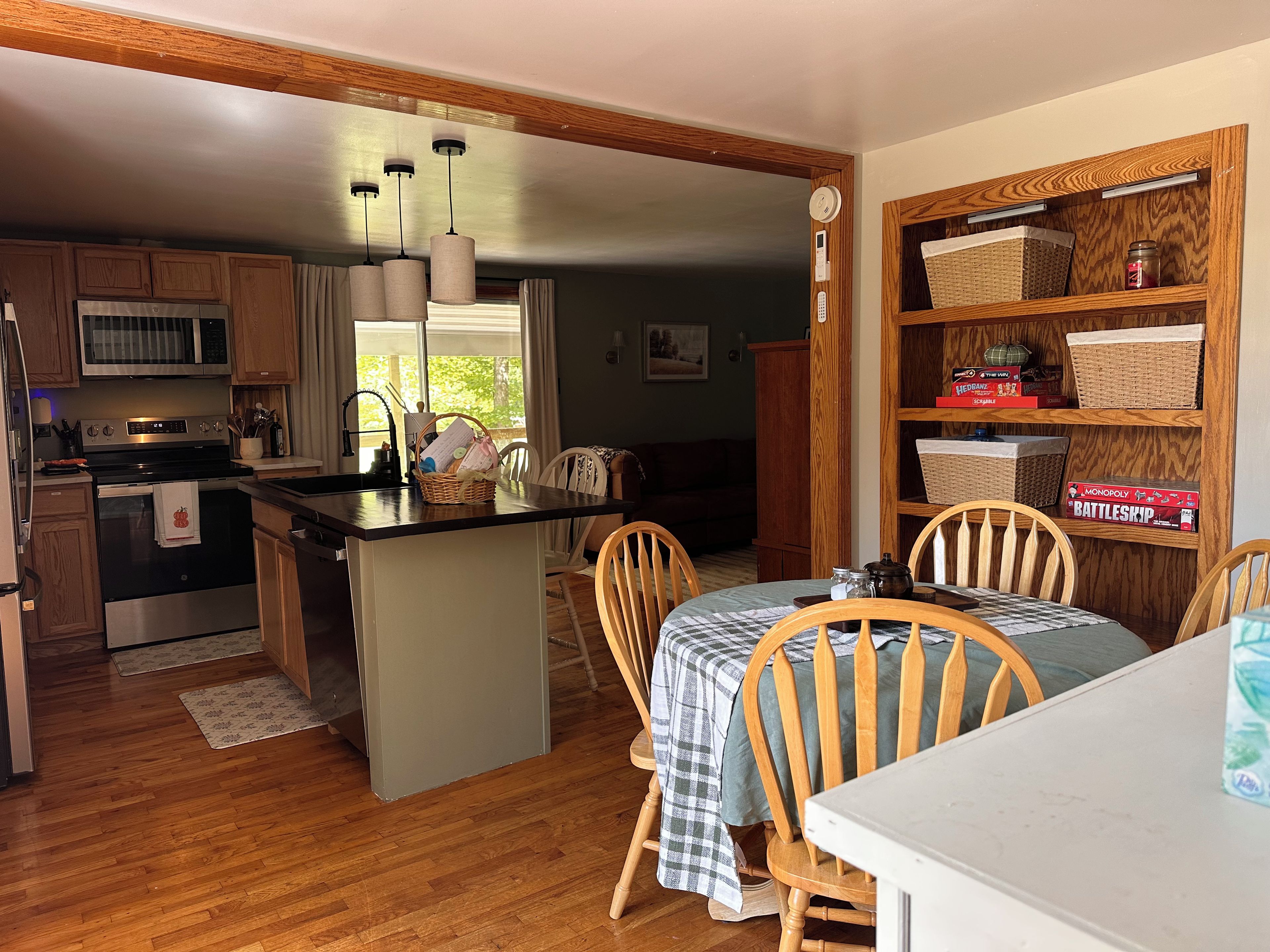 A kitchen with a central island, wooden cabinets, a microwave, and a dining area with chairs and a table.