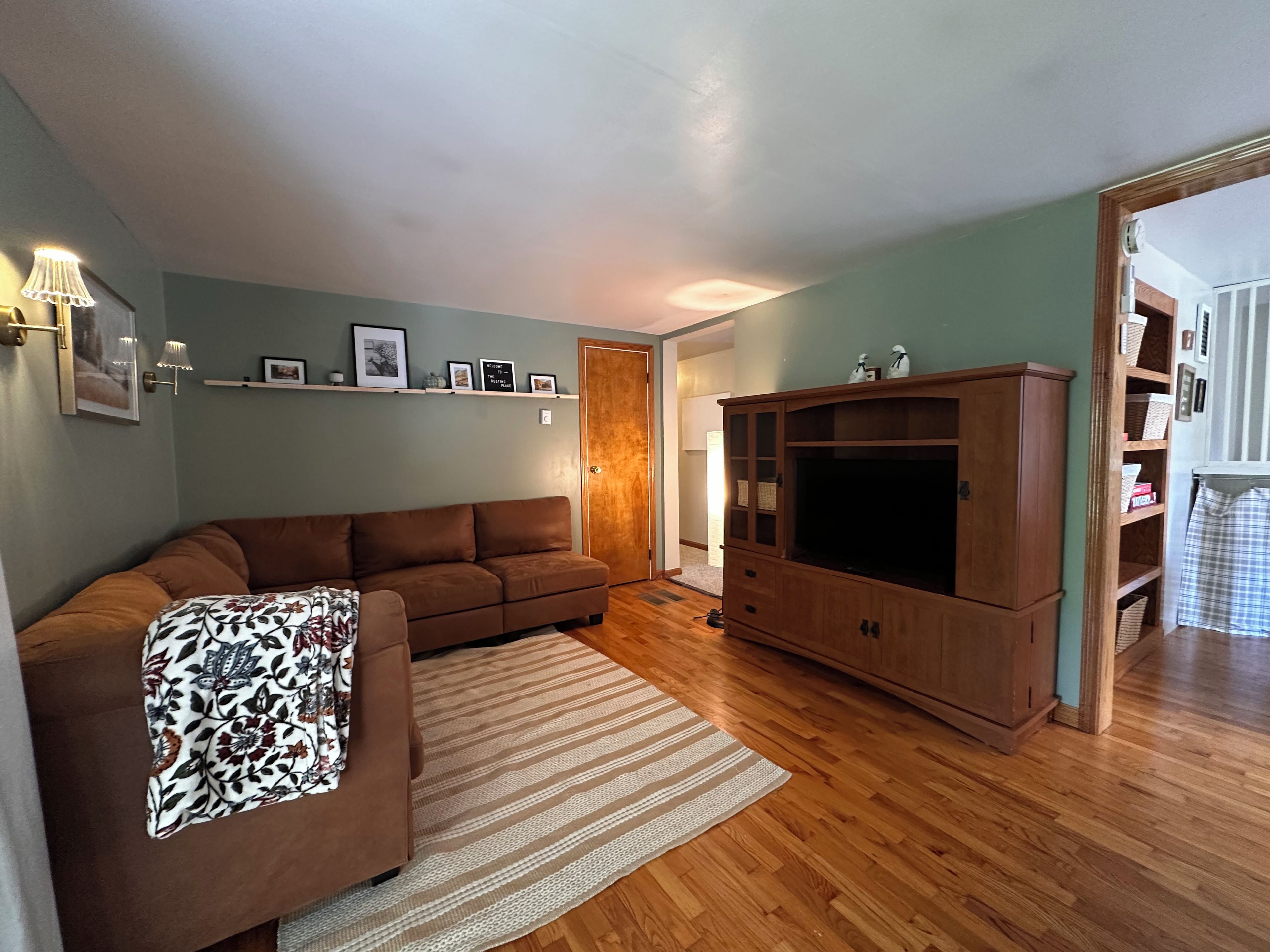 Una sala de estar con un sofá marrón, un mueble de entretenimiento de madera y un tapete a rayas.