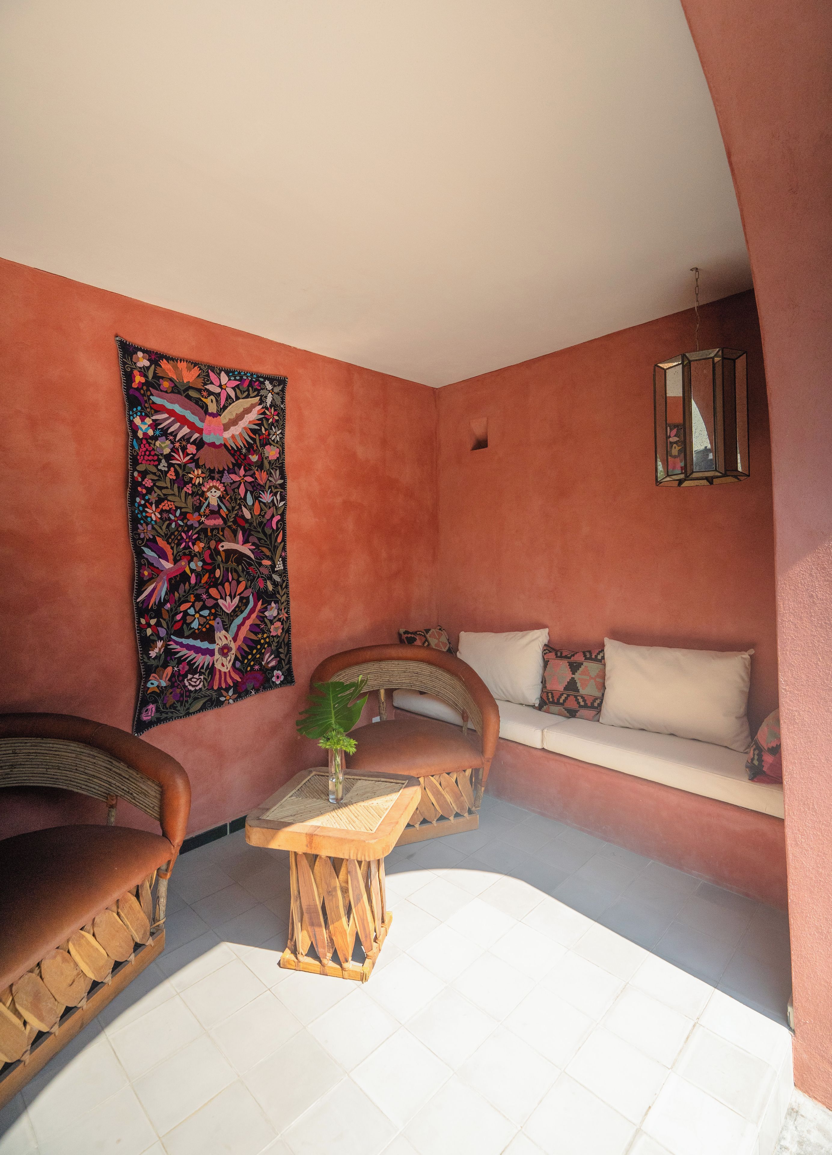 A cozy corner with a cushioned bench, a small table, and a vibrant tapestry on the wall.