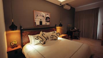 Habitación de hotel con una cama grande, lámparas de noche, un escritorio y un cuadro en la pared.