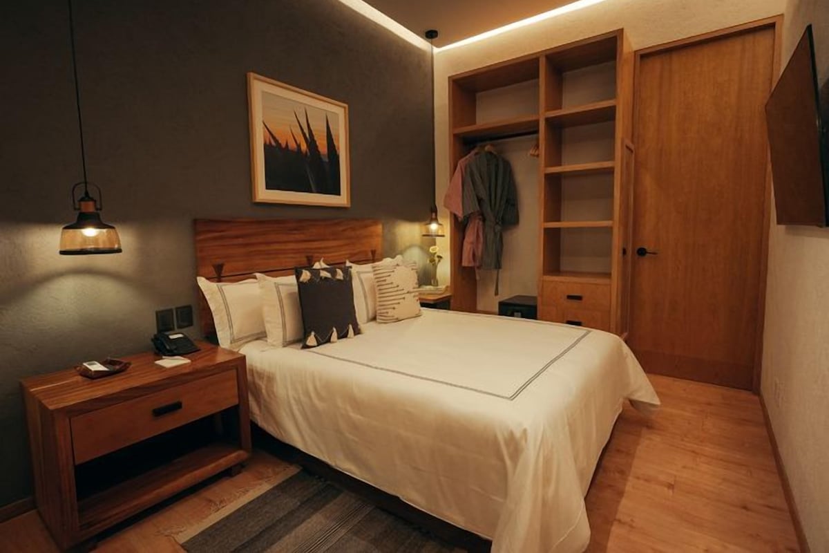 A bedroom with a bed, bedside table, lamp, and a wardrobe.