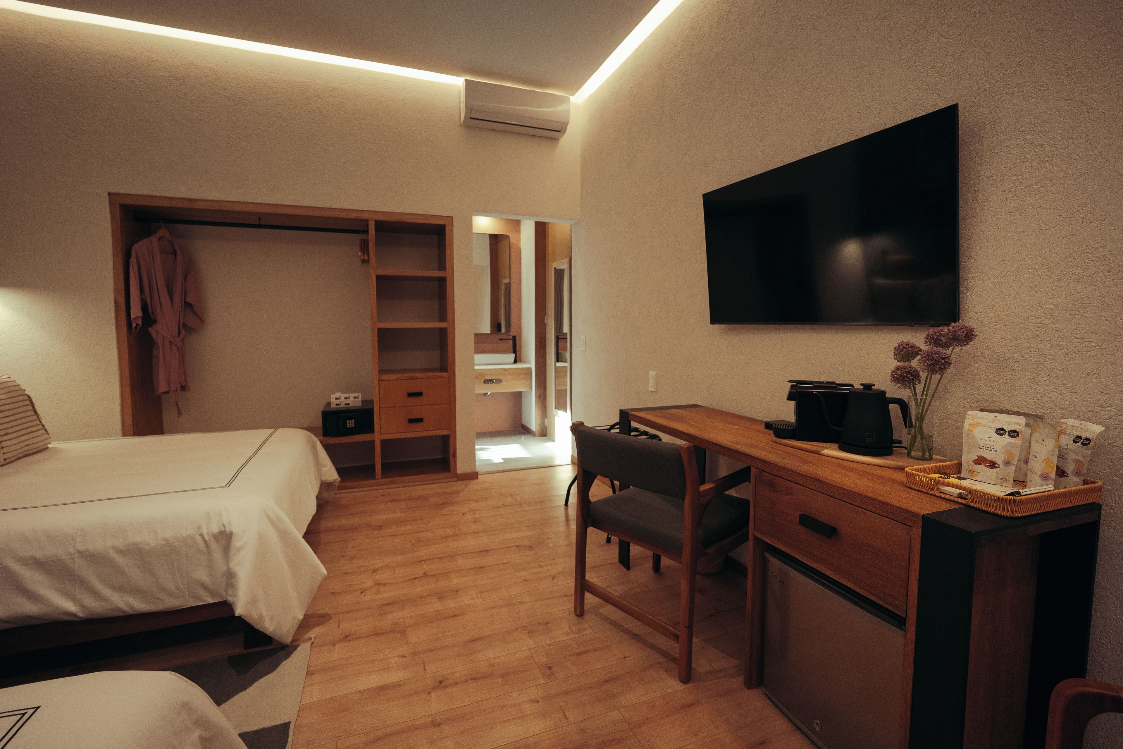A hotel room with a bed, a desk, a chair, a TV, and a wardrobe.