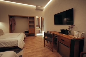 Una habitación de hotel con cama, escritorio, silla, televisor y armario.