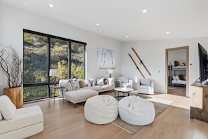 A modern living room with a large window, a sofa, a coffee table, and a TV. - Luxe West Vail Retreat W/Hot Tub, 8 Mins to Resort (Vail)