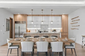 A modern kitchen with a central island, overhead lighting, and a dining area with a wooden table and chairs. - Luxe West Vail Retreat W/Hot Tub, 8 Mins to Resort (Vail)