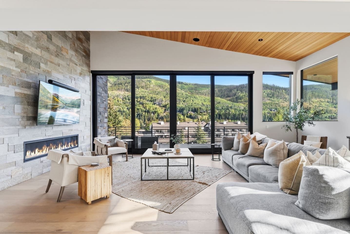 A modern living room with a fireplace, large windows, and a view of a mountainous landscape.