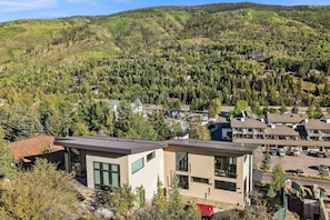 A modern building with large windows, surrounded by a forested area and a small parking lot. - Luxe West Vail Retreat W/Hot Tub, 8 Mins to Resort (Vail)