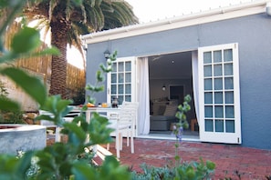 A residential property with a patio, a dining area, and a sliding glass door leading to an interior space. - Spacious, Modern Cottage between Mountains and Sea (Cape Town)