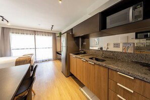Cozinha moderna com bancada de granito, eletrodomésticos de aço inoxidável e armários de madeira.