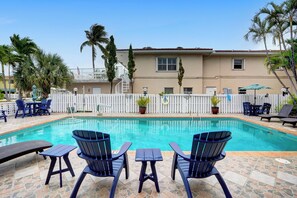 A swimming pool with lounge chairs and a white fence. - Tropical 1 Bed 1 Bath Apt Minutes to the Sea, Pool (Lauderdale-by-the-Sea)