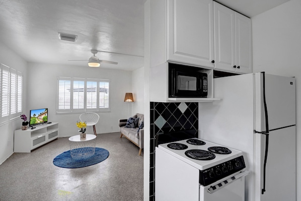 A modern kitchen with white cabinets, a black microwave, a white stove, and a built-in oven. - Tropical 1 Bed 1 Bath Apt Minutes to the Sea, Pool (Lauderdale-by-the-Sea)