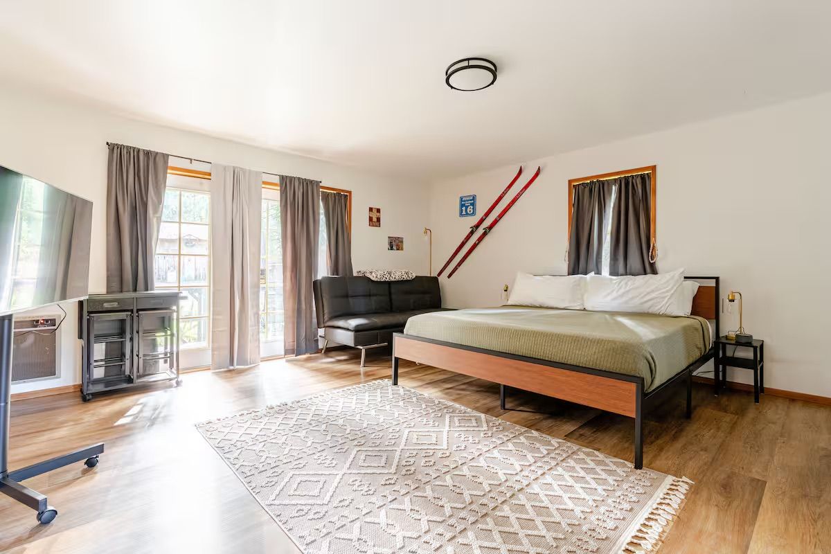 Ein Schlafzimmer mit einem Bett, einem Schreibtisch, einem Stuhl und einem Skiständer.