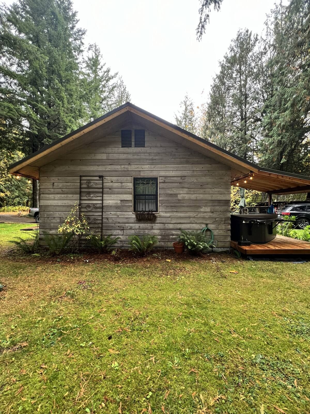A small wooden cabin with a sloped roof, a window with shutters, and a covered porch area.
