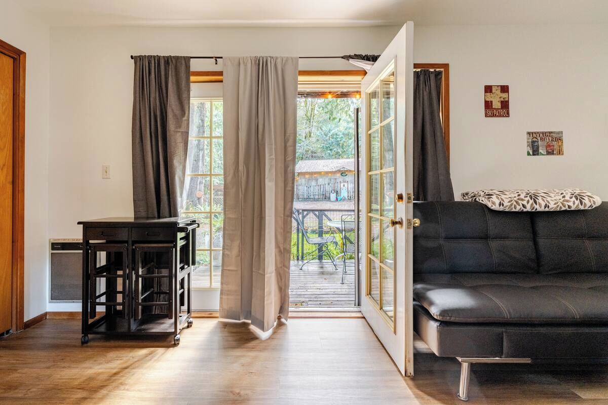 A room with a black sofa, a small table, and a sliding glass door leading to an outdoor area.