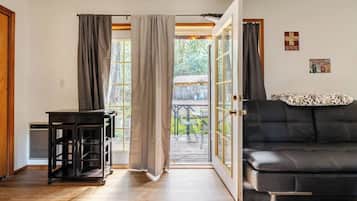 Una habitación con un sofá negro, una mesita y un ventanal corredero que da a un espacio exterior.